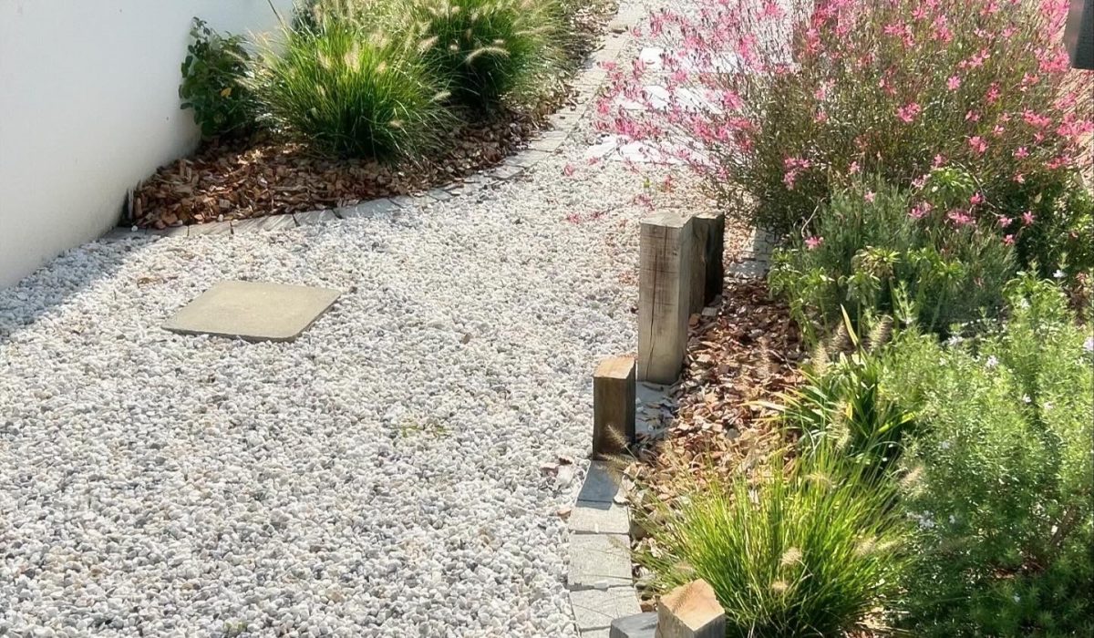 Massif de vivaces et allée gravillonnée avec bordures pavée et bois